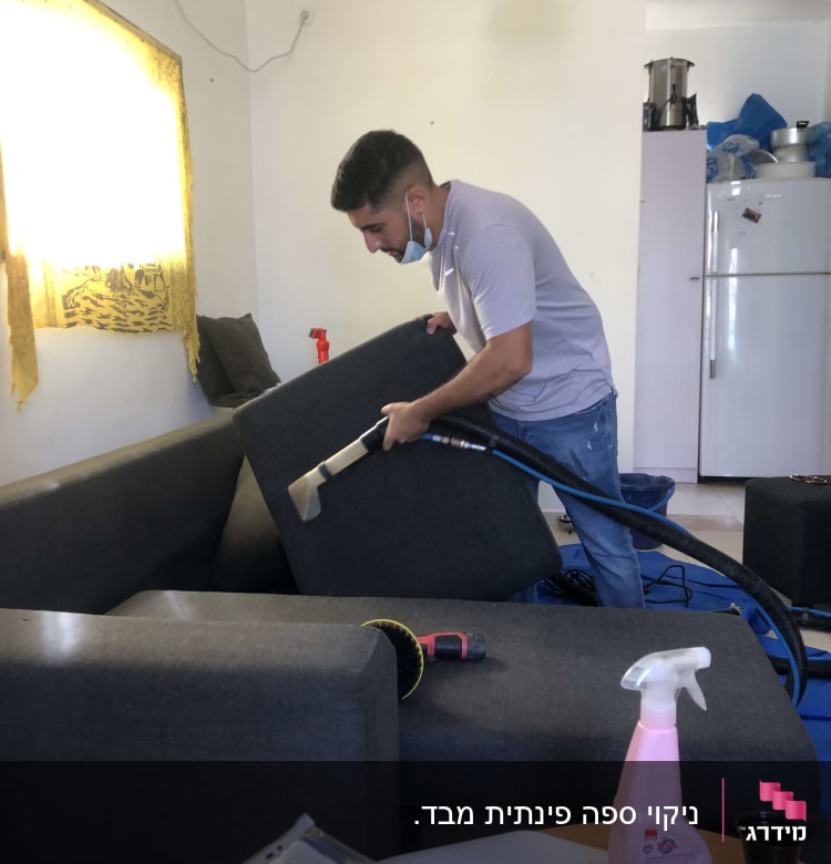 אדם מנקה ספה עם שואב אבק מקצועי